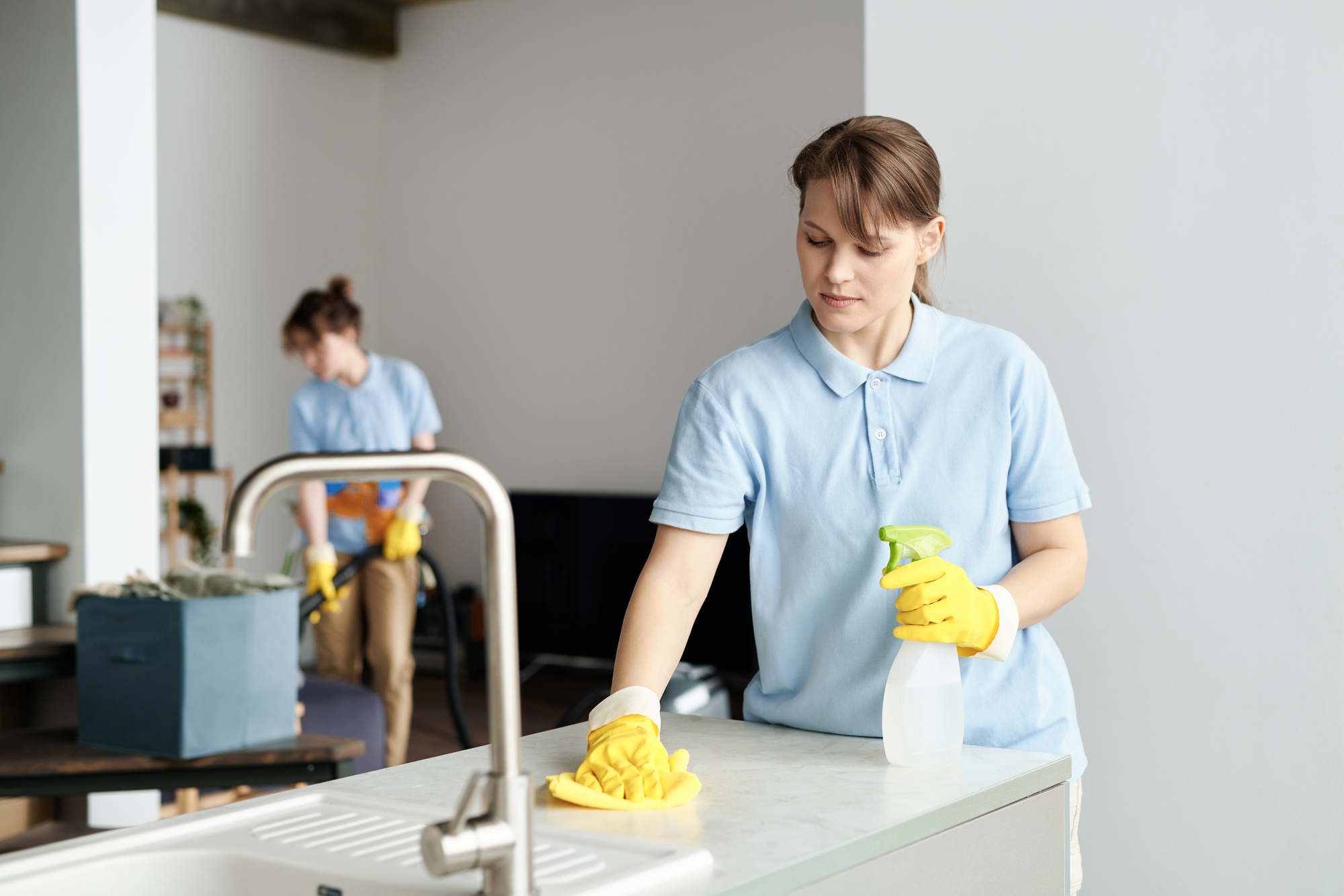 Woman wiping dust with her colleague Kitchen Cleaner